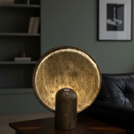 Antique gold eclipse accent lamp with textured circular disc and warm ambient lighting.
