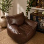 Brown leather lounge chair with soft cushioned seat and arms in a warm modern living room.