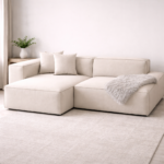 Cream L-shaped sectional sofa with low-profile modular design, plush linen upholstery, scatter cushions and a cozy grey throw, styled in a bright minimalist Japandi living room.