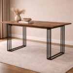 Walnut wood top dining table with black metal grid frame legs, decorated with pampas grass and a bowl on a light rug against a warm beige wall.