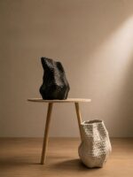 Black and ivory textured ceramic vase set with organic sculptural design on wooden table in minimalist modern interior