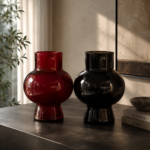 Ruby red and smoky black glass vase set on a modern table in a luxury living room.