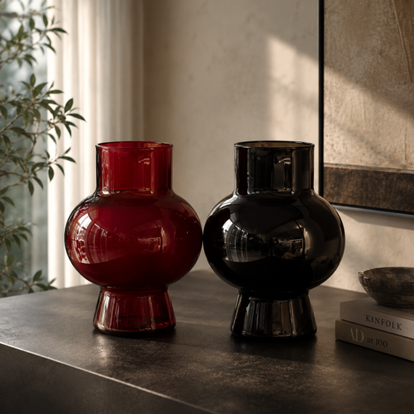 Ruby red and smoky black glass vase set on a modern table in a luxury living room.
