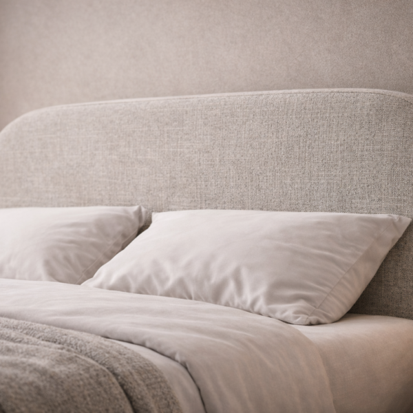 Beige upholstered bed with a curved headboard, textured fabric finish, white bedding, and modern bedside tables in a calm bedroom