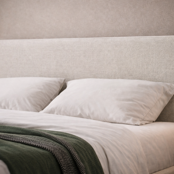 Cream upholstered bed with a curved headboard, soft fabric finish, white bedding, and modern bedside tables in a calm bedroom