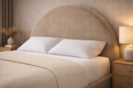 Arched upholstered bed with a curved headboard, textured beige fabric, white bedding, and modern bedside tables in a warm minimalist bedroom