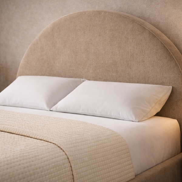 Arched upholstered bed with a curved headboard, textured beige fabric, white bedding, and modern bedside tables in a warm minimalist bedroom