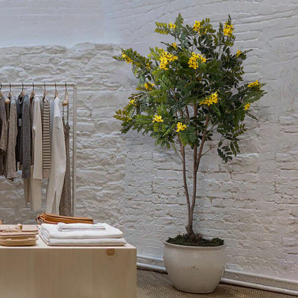 Artificial yellow flowering tree with realistic green foliage, vibrant yellow blossoms, and a natural-looking trunk for modern indoor home décor.