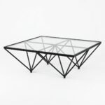 Vertex glass top coffee table with black geometric metal base, three-quarter view