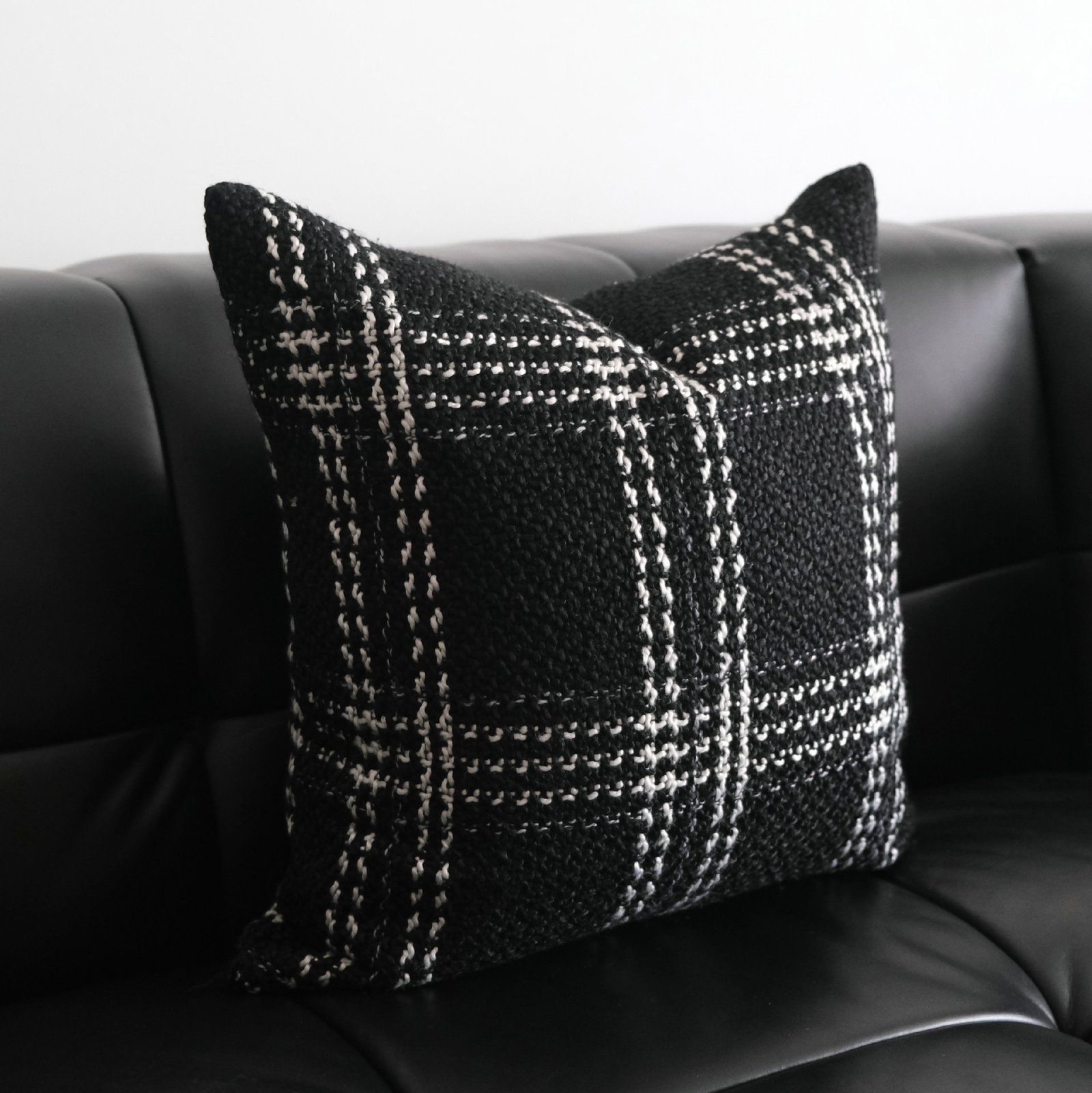 image-proxy Onyx black and grey plaid cushion on black leather sofa