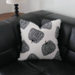 Maren black pumpkin motif cushion with white pumpkins on black leather sofa